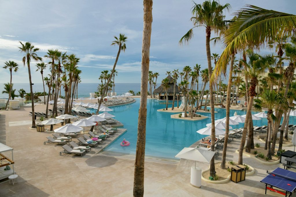 How much does it cost to buy a hotel: a beachfront resort pool lined with palm trees in Mexico
