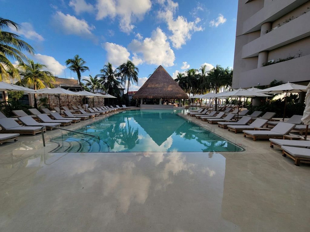 How to invest in hotels: a resort pool with a palapa bar and palm trees on the Caribbean coast